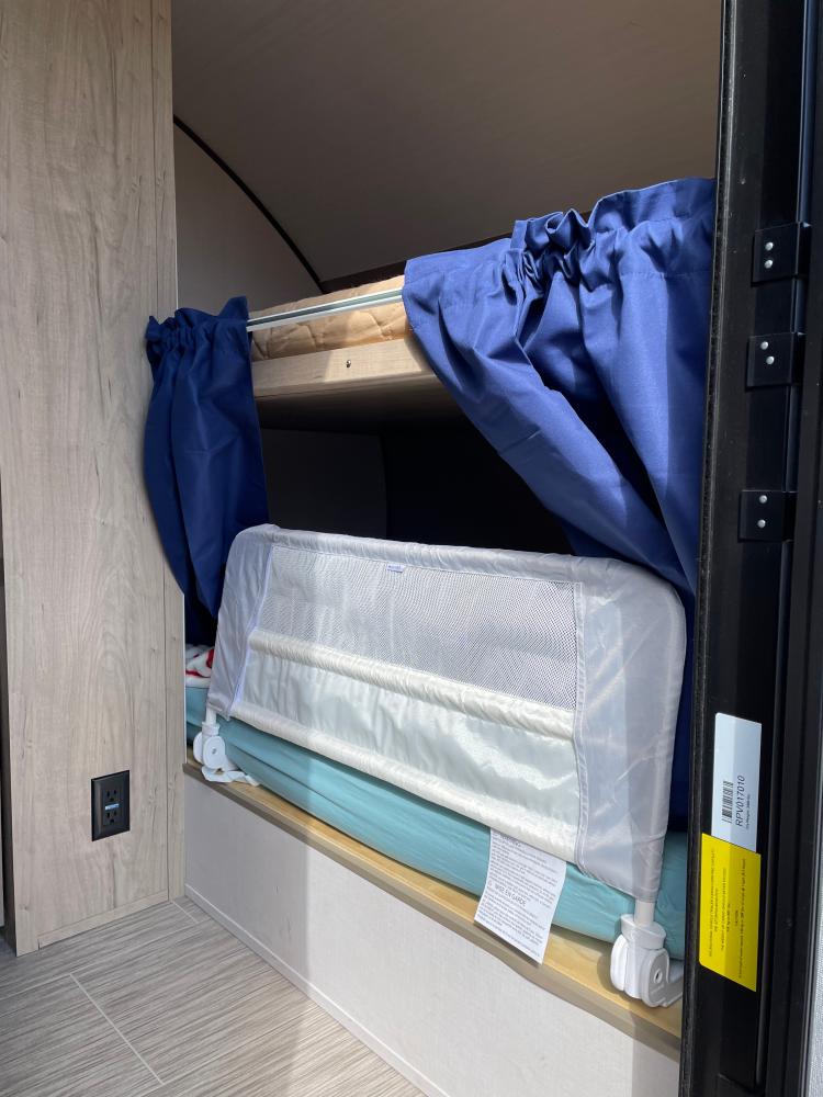 short blackout curtains hang on a tension rod in front of a bottom bunk rv bed
